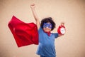 A portrait of kid boy in costume of superhero holdind alarm clock. Childhood, success and time management concept Royalty Free Stock Photo