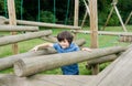 Portrait kid climbing on wooden fame in the park, Child enjoying activity in a climbing adventure park on summer sunny day, little Royalty Free Stock Photo