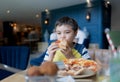 Portrait kid eating home made pizza in the cafe,  Happy Child boy biting off big slice of fresh made pizza in the restaurant, Royalty Free Stock Photo