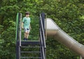 Portrait kid standing on slide at outdoor playground in summer., Child enjoying activity in a climbing adventure at park on summer Royalty Free Stock Photo