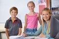 Portrait, kids with teacher and woman in classroom, smile and working in class. Happiness, female educator and group of