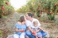 Portrait of kissing parents with baby girl daughter having rest and fun in the pomegrate fruit garden on the sunset. Happy family Royalty Free Stock Photo