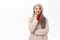 Portrait of korean businesswoman, woman with grey hair thinking, wearing suit, smiling intrigued, standing over white Royalty Free Stock Photo