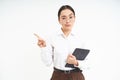 Portrait of korean corporate woman in glasses, holds digital tablet, points finger left and looks strict and serious