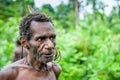 The Portrait Korowai man on the natural green forest background.