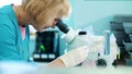 portrait of lab worker, biochemist in white gloves, studying, examines something with microscope, in laboratory. Science