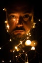 Portrait of a large-eyed Caucasian man subtly illuminated by Christmas lights