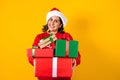 Portrait of Latin adult woman holding Christmas gift box on a yellow background in Mexico latin america Royalty Free Stock Photo