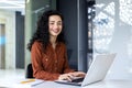 Portrait of Latin American business woman, office worker looking at camera and smiling, using headset and laptop for Royalty Free Stock Photo