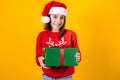 Portrait of Latin child girl holding Christmas gift box on a yellow background in Mexico latin america Royalty Free Stock Photo