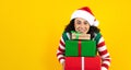 Portrait of Latin mature woman holding Christmas gift box on a yellow background in Mexico latin america Royalty Free Stock Photo