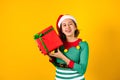 Portrait of Latin teenager girl holding Christmas gift box on a yellow background in Mexico latin america Royalty Free Stock Photo