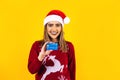 Portrait of Latin woman holding a credit card for shopping at Christmas wearing a santa hat on yellow background in Mexico latin A Royalty Free Stock Photo