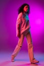 Portrait of Latino beautiful happy girl dancing on purple, lilac color studio background in neon light. Concept