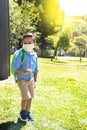 Portrait of a Latino boy walking in a park with his backpack and mask Royalty Free Stock Photo