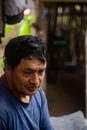 Portrait of a Latino male looking down with a frown while sitting outside his house Royalty Free Stock Photo