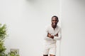 Laughing african american man with arms crossed leaning against white wall Royalty Free Stock Photo