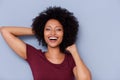 Laughing african american woman with hands in curly hair on gray background