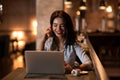 Portrait of laughing and beautiful businesswoman speaking on the phone and working on her laptop in modern restaurant. Royalty Free Stock Photo