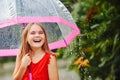 Portrait of a laughing beautiful little girl in the rain, with a