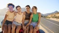 Portrait Of Laughing Female Friends Sitting On Hood Of Open Top Car On Road Trip Royalty Free Stock Photo