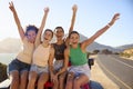 Portrait Of Laughing Female Friends Sitting On Hood Of Open Top Car On Road Trip Royalty Free Stock Photo