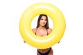 Portrait of a laughing girl dressed in swimsuit looking through inflatable ring isolated over white background