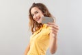 Portrait of laughing girlish woman with long hair do wear yellow top. Hand showing credit card isolated on white background Royalty Free Stock Photo