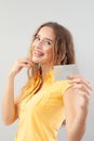 Portrait of laughing girlish woman with long hair do wear yellow top. Hand showing credit card isolated on white background Royalty Free Stock Photo