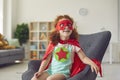 Portrait of laughing happy red haired girl in costume of superhero star sitting on armchair and smiling Royalty Free Stock Photo