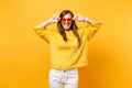 Portrait of laughing happy young woman in fur sweater, white pants holding heart orange eyeglasses isolated on bright Royalty Free Stock Photo