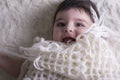 Portrait of laughing little baby girl under knitted cloth