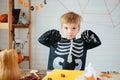 Portrait of laughing little boy in a skeleton costume is ready to celebrate Halloween. Boy in a halloween dress-up room.