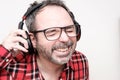 Portrait of a laughing mature man with beard wearing red plaid shirt and glasses. Wearing headphones Royalty Free Stock Photo