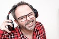 Portrait of a laughing mature man with beard wearing red plaid shirt and glasses. Wearing headphones Royalty Free Stock Photo