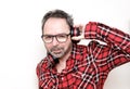 Portrait of a laughing mature man with beard wearing red plaid shirt and glasses. Wearing headphones Royalty Free Stock Photo