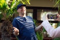 Portrait of laughing middle-aged man blogger traveller stand recording educational video with smartphone held by woman.