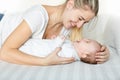 Portrait of laughing 3 months old baby boy and young woman lying on bed Royalty Free Stock Photo