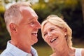 Portrait Of Laughing Senior Couple In Garden At Home Together