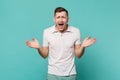 Portrait of laughing smirked young man in casual clothes standing, spreading hands isolated on blue turquoise wall Royalty Free Stock Photo