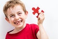 Laughing toothless boy finding jigsaw for concept of fun education