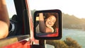 Portrait Of Laughing Woman Reflected In Car Wing Mirror Having Fun In Open Top Car On Road Trip