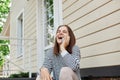 Portrait of laughing young adult woman talking with mobile phone outdoor near building communicating with friends having good time