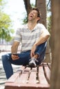 Laughing young man sitting outdoors on bench with cell phone Royalty Free Stock Photo