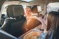 Portrait of laughing young woman with Italian pizza while she traveling with family in a modern car. Happy family moments and Royalty Free Stock Photo