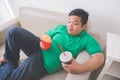 Lazy obese person eats junk food while laying on a couch