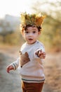 Portrait liitle boy with crown of leaves in autumn park. Cute curly toddler