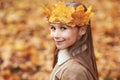 Portrait liitle cute girl with crown of leaves in autumn park