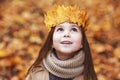 Portrait liitle cute girl with crown of leaves in autumn park