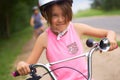 Portrait of a litte girl in a pink safety helmet driving her bike.